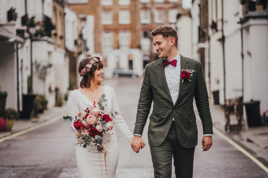 Bride and groom walking hand in hand in a mews