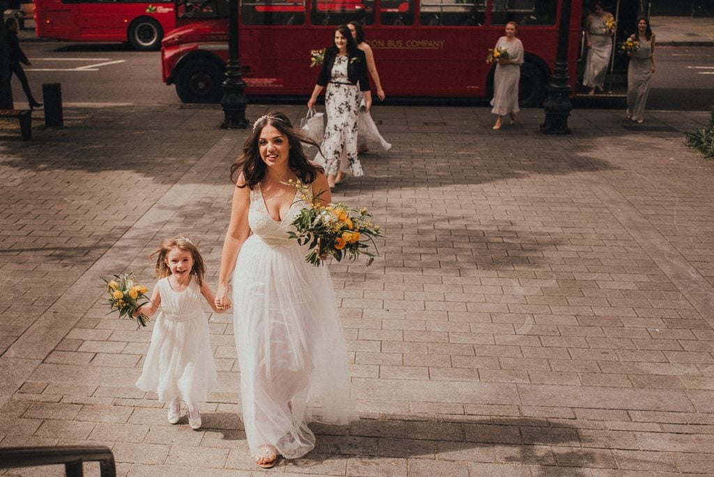 bride walks into wedding venue with flower girl