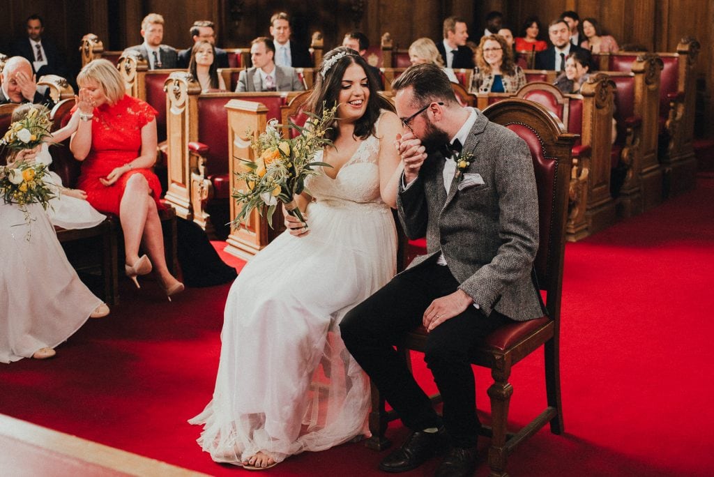 groom kisses bride's hand during ceremony
