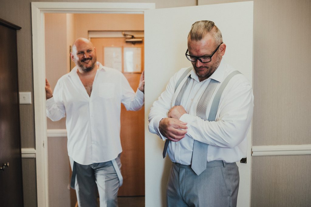 groom's brothers laughing as he gets ready