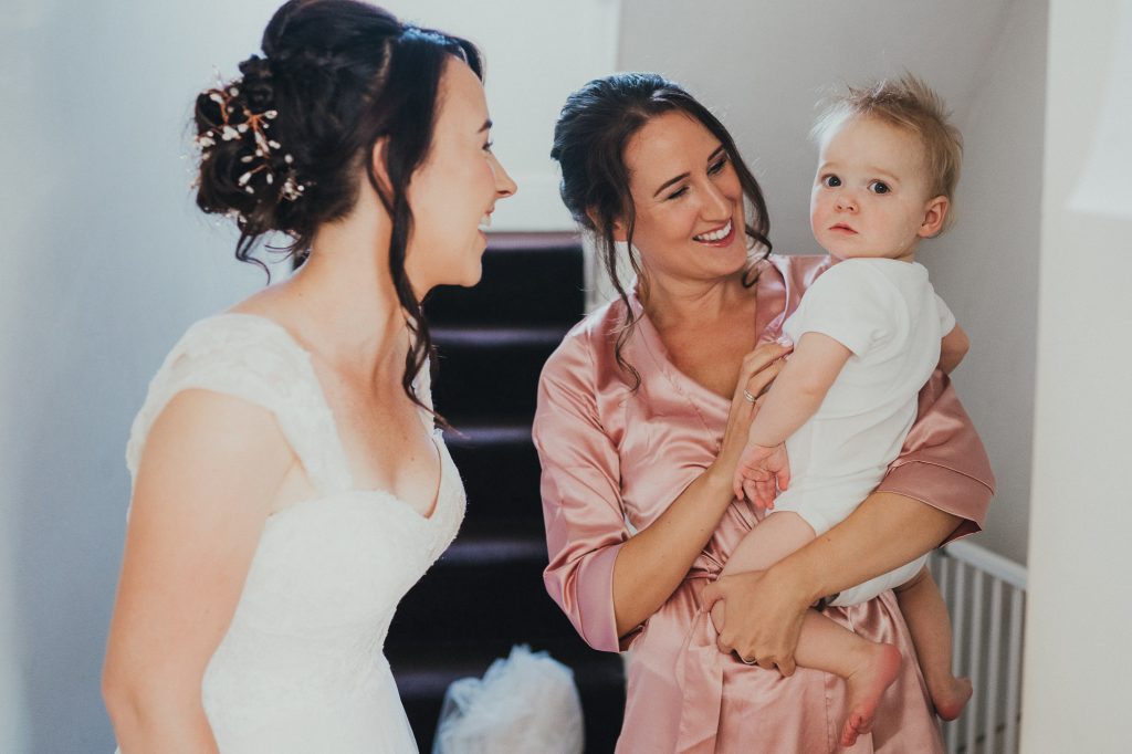 bride laughs with her bridesmaid and baby