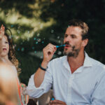 father blowing bubbles for his daughter