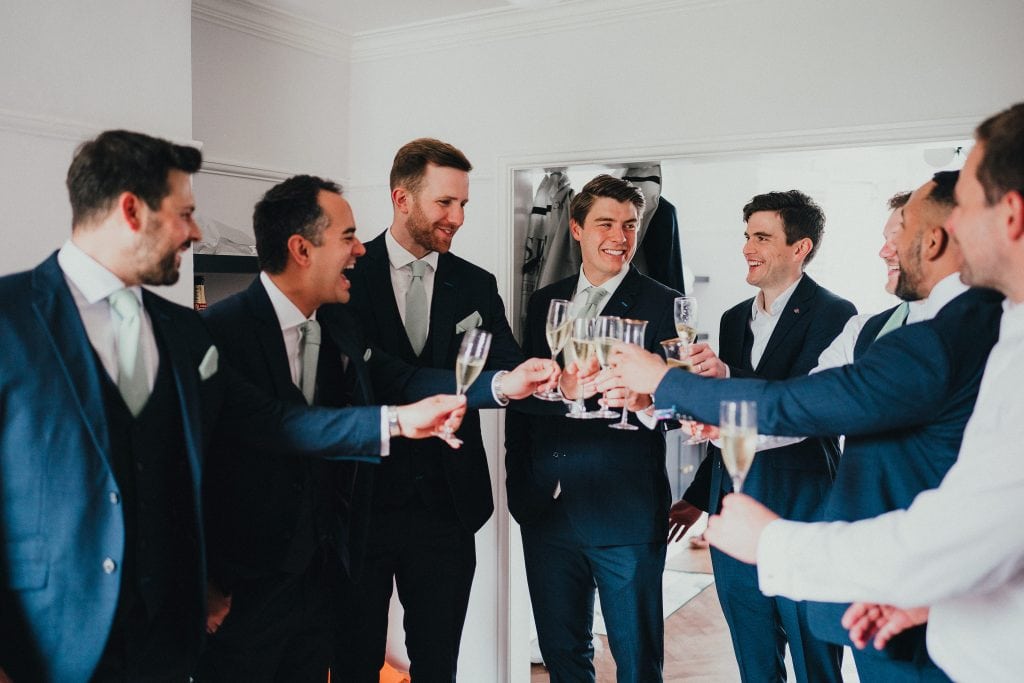 Groom and ushers drinking champagne