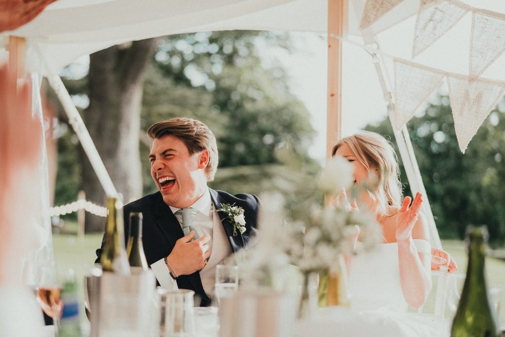 bride and groom laughing at speech