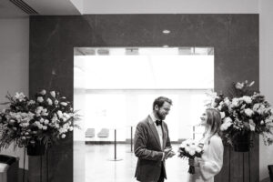 Couple with flowers at elegant indoor wedding venue.