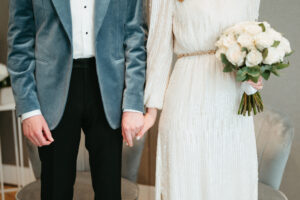 Bride and groom holding hands with bouquet
