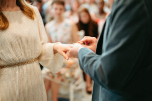 Bride receiving ring during wedding ceremony.