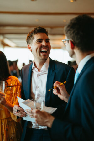 Man laughing at social event with friends.