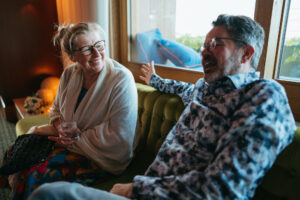 Two adults laughing and conversing on sofa.
