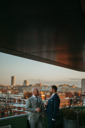 Two men conversing on rooftop at sunset