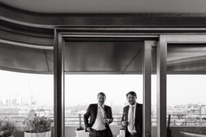 Two men toasting drinks at a rooftop event.