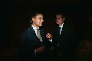 Two men in suits smiling and conversing at event.