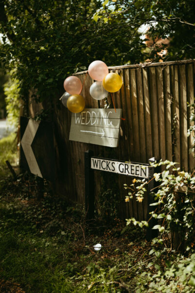 Wedding sign with balloons on wooden fence.