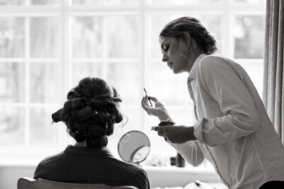 Makeup artist applying cosmetics to woman indoors.