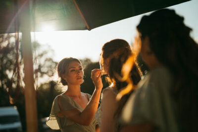 Bride getting makeup done outdoors at sunset
