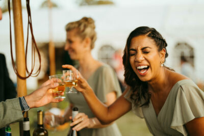 Women toasting at outdoor celebration, laughing.