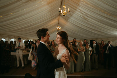 Couple dancing at wedding reception under tent.