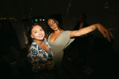 Two women dancing at a party with live music.