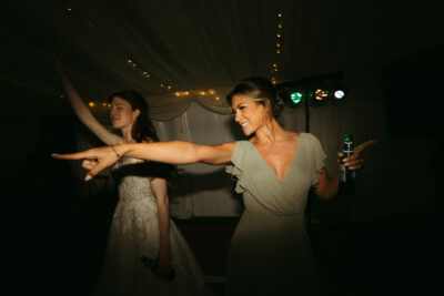 Women dancing joyfully at evening wedding reception.