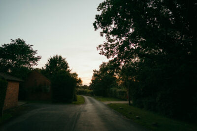 Twilight over a quiet rural road with trees.
