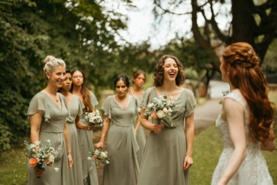 Bride laughing with bridesmaids outdoors.