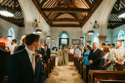 Wedding guests waiting in church aisle.