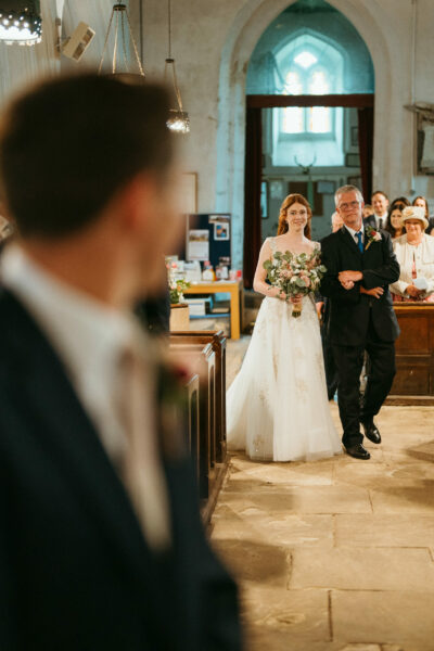 Bride escorted by father in church aisle.