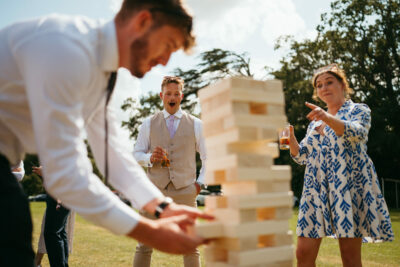 Guests playing giant Jenga at outdoor event.