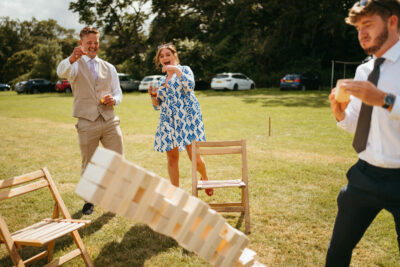Guests playing giant Jenga at outdoor event.