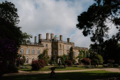 Historic mansion with lush garden and trees.
