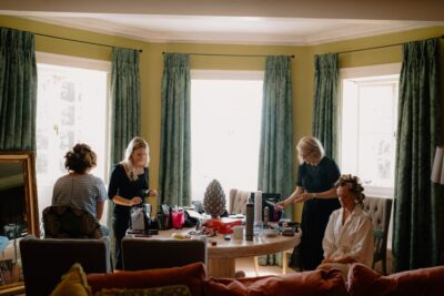 Women preparing for an event in bright room.