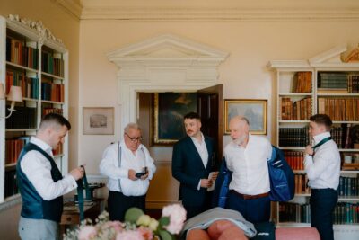 Men preparing for a formal event in library.