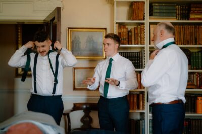 Groomsmen preparing ties in a library setting.