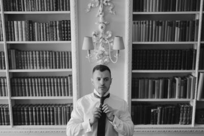 Man adjusting tie in library