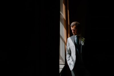Man in suit standing by window, dramatic lighting