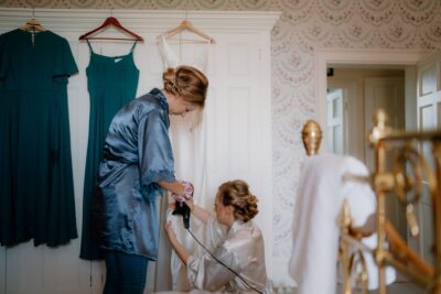 Bridesmaid steams wedding dress in preparation room.