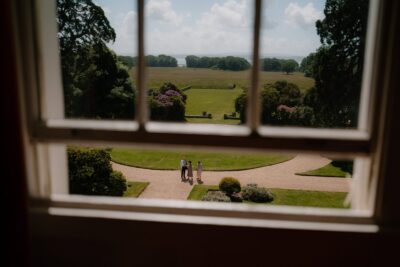 Group walking in garden viewed through window.