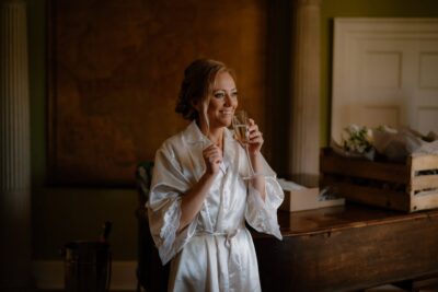 Woman in robe enjoying champagne indoors.