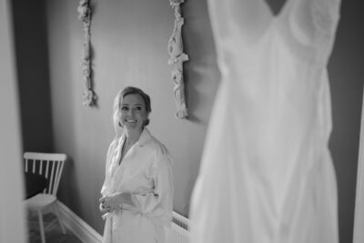 Bride smiling near wedding dress indoors