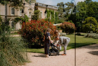 Family with pram outside historic building garden