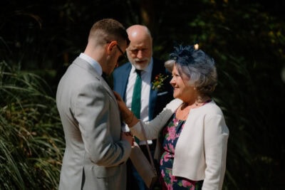 Woman adjusts man's suit at outdoor event