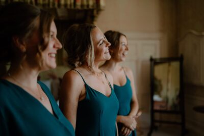 Three bridesmaids smiling in green dresses indoors.