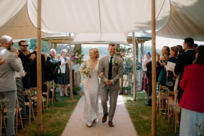 Bride and groom walking down aisle, guests clapping.