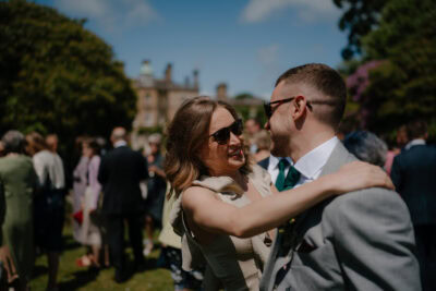Couple embracing at outdoor event, lush background.