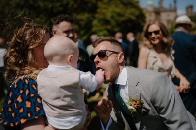 Man playfully interacting with baby's hand at event.