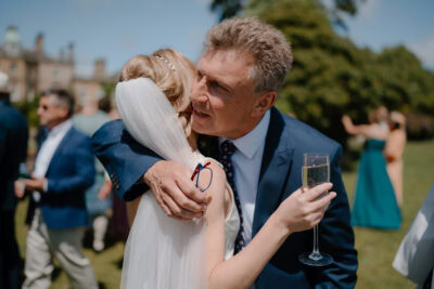 Bride hugging guest at outdoor wedding celebration.