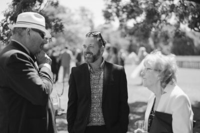 Three people socialising outdoors at a formal event.