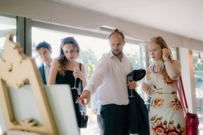 Group observing an artwork with drinks in hand.