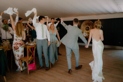 Wedding guests cheering bride and groom entering reception.