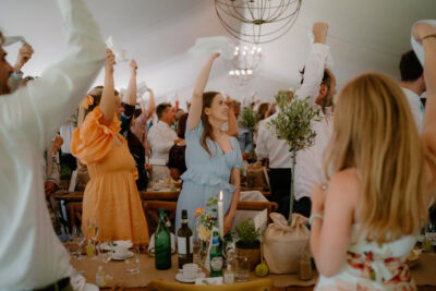 People celebrating at a wedding reception under marquee.